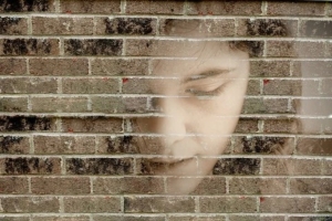 Volto di un ragazzo sovrapposto a un muro di mattoni