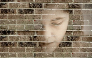 Volto di un ragazzo sovrapposto a un muro di mattoni