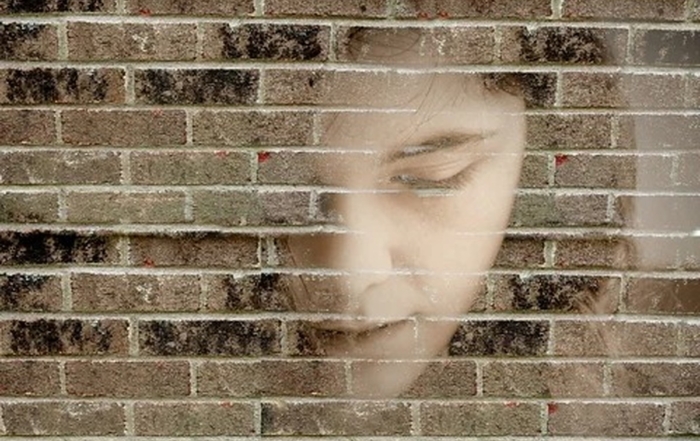 Volto di un ragazzo sovrapposto a un muro di mattoni